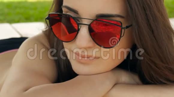 漂亮的年轻女孩戴着镜子眼镜躺在海滩上视频的预览图