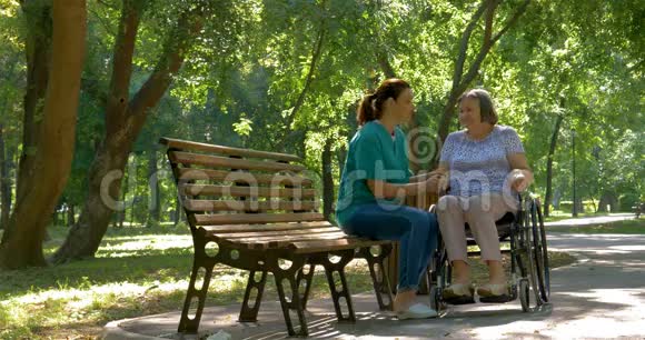 照顾者在户外轮椅上与残疾老年妇女交谈视频的预览图