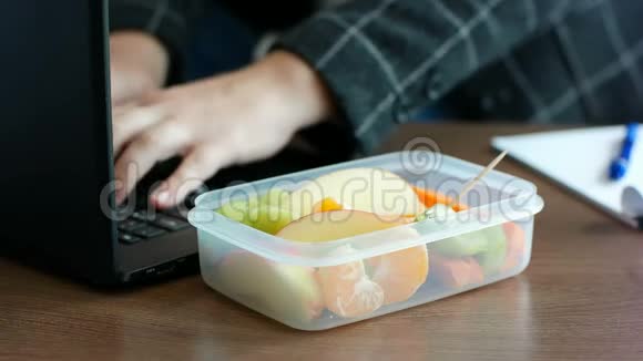 这位西装革履的女商人在笔记本电脑上工作在饭盒里吃水果零食视频的预览图
