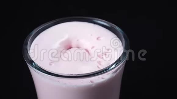 特写新鲜草莓奶昔和草莓落在玻璃里框架黑色背景视频的预览图