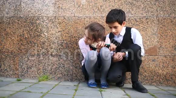 伤心的男孩和女孩坐在街上看着你的手机视频的预览图