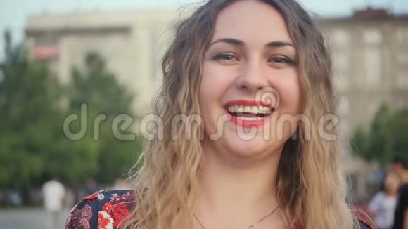 一个快乐的微笑的女人在城市的街道上热烈地笑可爱的白种人女子夏季特写肖像视频的预览图