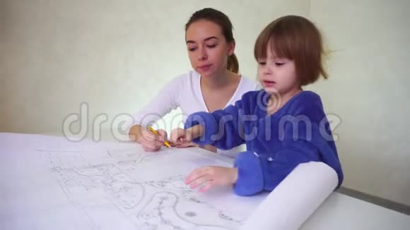 年轻的母亲帮助女儿画画集中精力的女孩坐在光线充足的房间里讨论职业视频的预览图