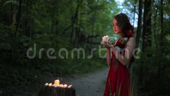 不寻常的女孩有创意的化妆在黑暗的森林里拿着两支燃烧的蜡烛视频的预览图