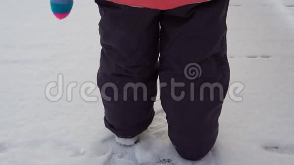 一个穿着暖和的衣服的孩子走过雪地他的脚留下了痕迹视频的预览图