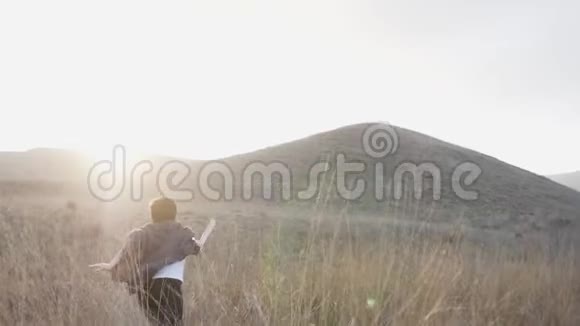 日落时分一个拿着剑的男孩在草地上跑向地平线慢动作视频视频的预览图