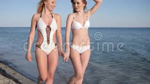 海岸的女朋友光着脚在沙滩上散步海洋附近度假岸上穿泳装的女孩热带夏季周末视频的预览图