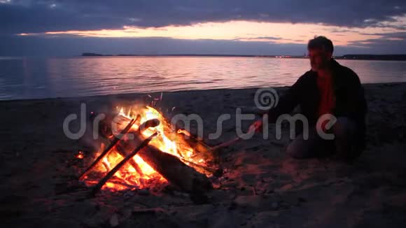 日落时分人们正在向河岸的火堆扔柴视频的预览图