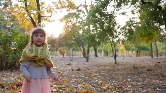 孩子在阳光下玩肥皂泡快乐的小女孩在秋天笑视频的预览图