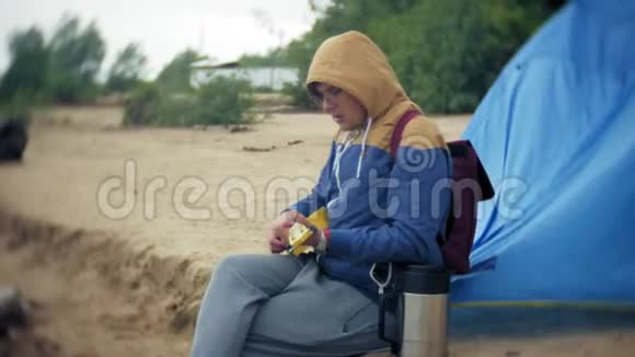 一个人在一个旅游帐篷附近河岸的四弦琴上玩耍视频的预览图