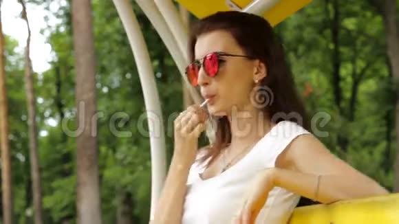 戴眼镜的时髦年轻女性吸棒棒糖视频的预览图
