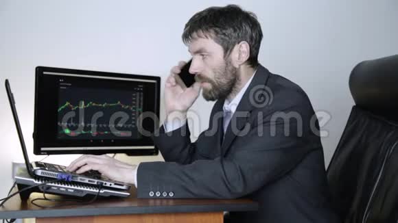 交易员在电话上为客户提供建议并在笔记本电脑上观看货币兑换图表密码证券交易所的工作视频的预览图