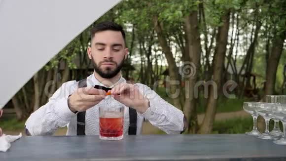 酒保把橙汁挤成一杯加冰的威士忌酒保在酒吧柜台上提供冰镇鸡尾酒视频的预览图