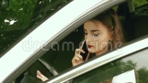 时髦的黑发少女坐在车里通过电话说视频的预览图