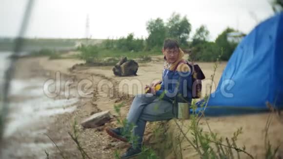 一个人在一个旅游帐篷附近河岸的四弦琴上玩耍视频的预览图