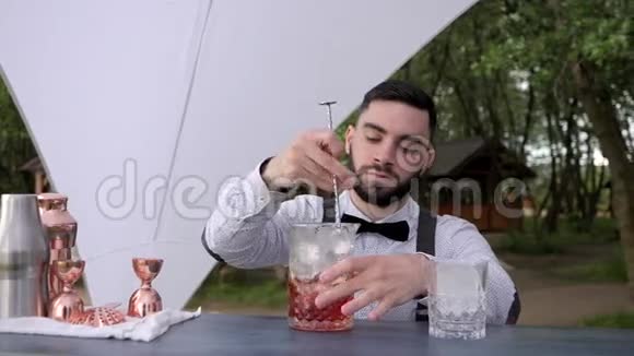 酒吧柜台的酒吧服务员用冰块搅拌酒精酒吧服务员在户外饮用酒精饮料视频的预览图