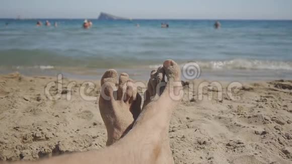 白种人的脚的角度躺在海边的沙滩上视频的预览图