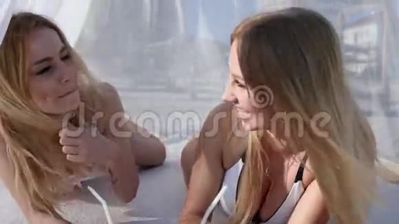 在海滩上友好的亲吻穿着泳衣的漂亮女朋友在海边休息年轻女人手中的异国水果视频的预览图