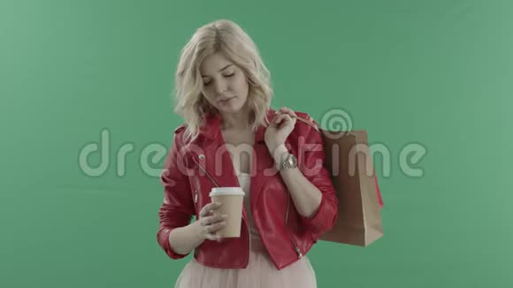 迷人的女顾客喝咖啡拿着袋子对着绿色的屏幕视频的预览图