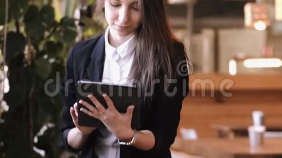 漂亮的黑发商务女性坐在木桌旁拿着平板电脑工作视频的预览图