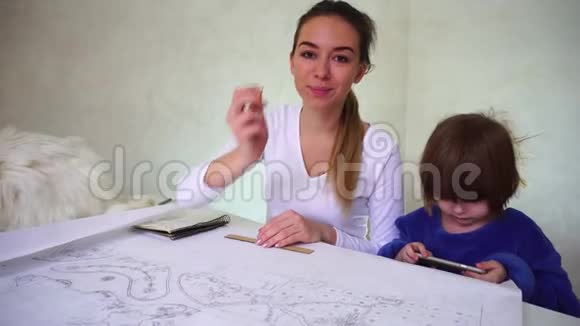两个姐妹坐在桌子旁拿着Whatman纸白猫躺在女孩身边视频的预览图
