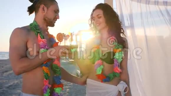 爱在背光的人站在夏威夷海滩夫妇喝鸡尾酒穿花夏威夷雷白布视频的预览图