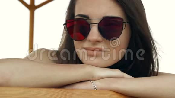 海滩上戴着明亮眼镜的迷人女孩视频的预览图
