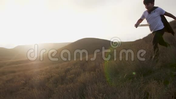 日落时分一个拿着剑的男孩在草地上跑向地平线慢动作视频视频的预览图