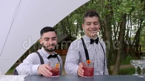 酒吧后面的微笑调酒师供应鸡尾酒酒吧服务员用玻璃做冷饮调酒师装饰鸡尾酒视频的预览图
