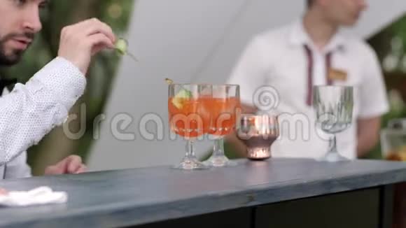 酒保为顾客提供饮料酒保装饰鸡尾酒酒吧老板在酒吧后面做彩色鸡尾酒视频的预览图