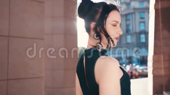 一位穿着一件小黑裙戴着大耳环走出办公室的优雅年轻女子的后景视频的预览图