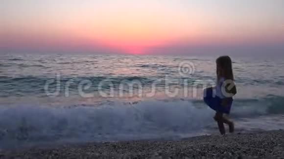 沙滩在海滩上玩耍女孩在海岸线上散步日落时的海浪景观4K视频的预览图
