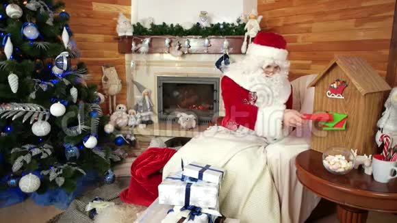 圣诞老人把礼物放进口袋里圣诞老人邮筒里圣尼古拉斯把孩子们的愿望清单上的礼物打包视频的预览图