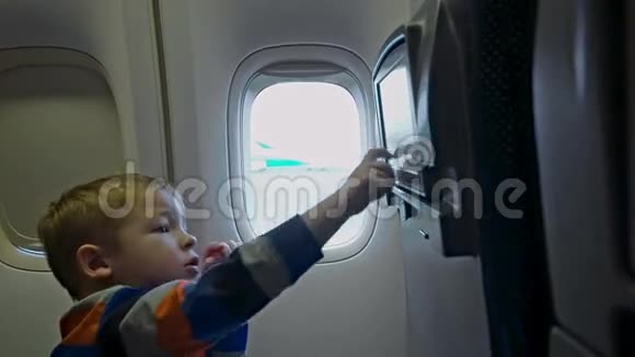 小男孩在飞机上触摸座椅监视器视频的预览图