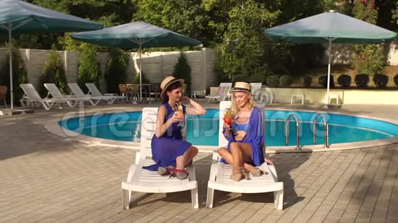 两个穿比基尼的女孩在泳池边喝鸡尾酒视频的预览图
