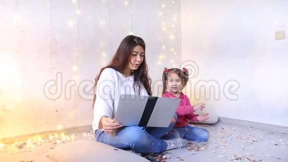 年轻的母亲和小女儿坐在地板上在网上商店购物视频的预览图