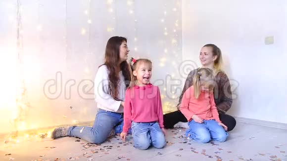 两个快乐的年轻妈妈坐在地板上和小女儿玩视频的预览图