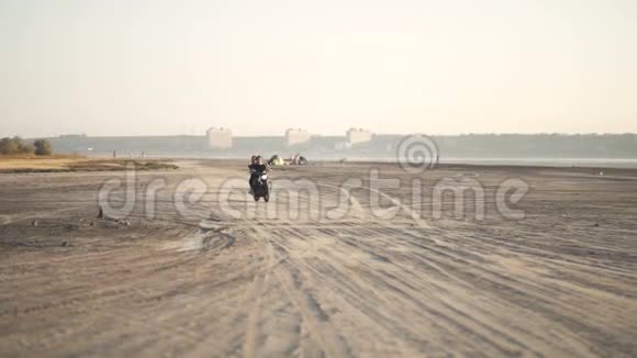 美丽的年轻女子摩托车手和他的女朋友骑摩托车在沙漠日落或日出两个女人跳舞视频的预览图