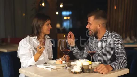 年轻夫妇在约会一个男人给他的女人吃美味的甜点一对夫妇在餐馆里笑视频的预览图