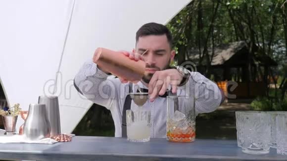 酒保将利口酒慢慢倒入准备好的酒杯中酒吧工作人员通过过滤器准备鸡尾酒视频的预览图