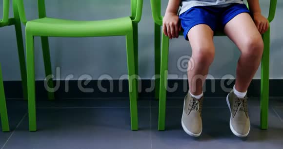 坐在医院走廊椅子上的坐着不舒服的男孩视频的预览图