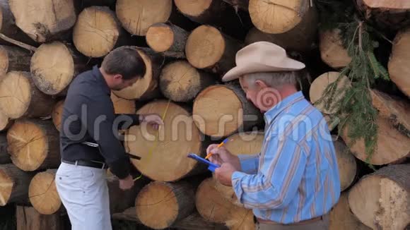 锯木厂的员工测量原木树的末端并写出结果视频的预览图