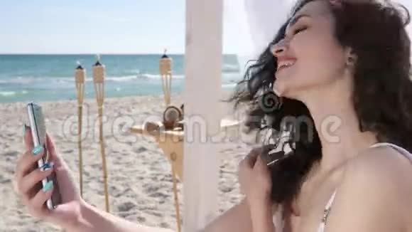 女人自拍微笑的女孩在海滩上用手机拍照夏天旅行的视频女性视频的预览图