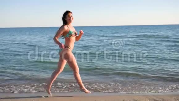 微笑的女人跑着海水穿着泳衣走着视频的预览图