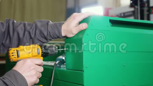 绿色金属机械中使用电动手电钻成孔的工人视频的预览图