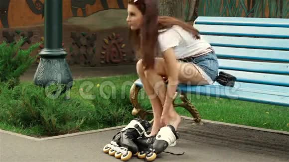一个年轻女孩坐在公园的长凳上把滚筒移开视频的预览图