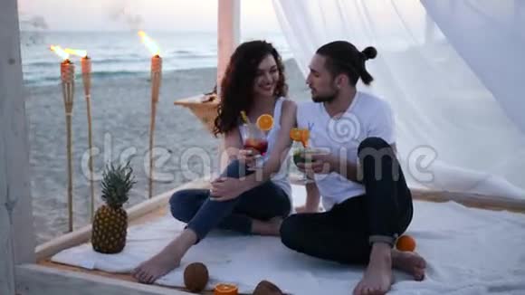 暑假恋爱中的年轻人喝着五颜六色的鸡尾酒和水果浪漫的情侣在热带海滩视频的预览图