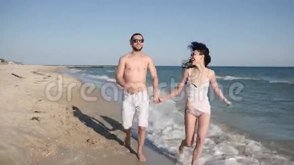 度假情侣在异国的岛屿上相爱情侣在沙滩上赤脚行走海滩全景快乐的朋友视频的预览图