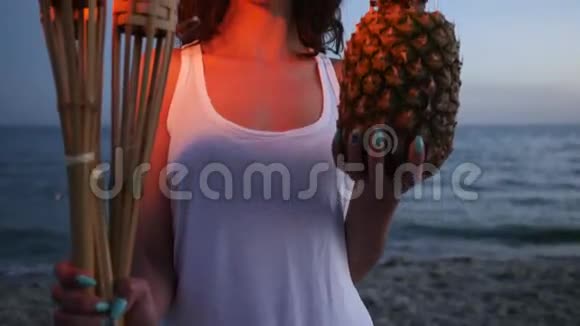 女性手持燃烧的火炬和菠萝热带岛屿背景海洋和沙滩空滩夏季休息视频的预览图