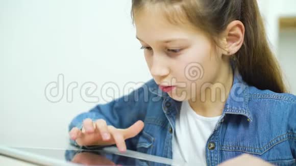 兴奋的小女孩在网上玩游戏时触摸平板电脑屏幕视频的预览图